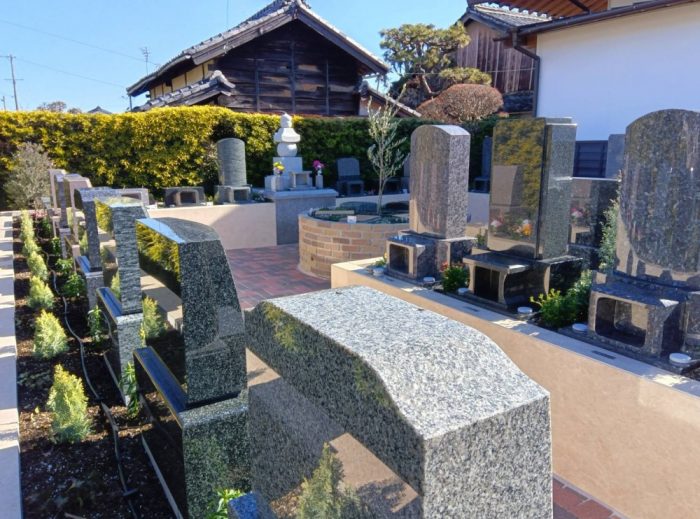 新城はなえみ墓園の全景。花と緑に囲まれた明るい雰囲気の墓園で、整然と並ぶ墓石と青空が見える