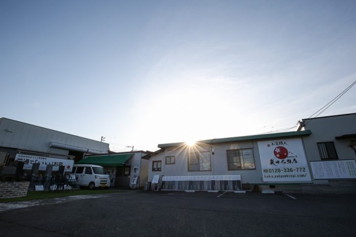 矢田石材店岡崎本店の外観写真。看板が明確に見え、展示墓石が並ぶ清潔感のある店舗。駐車場も確認でき、入りやすい雰囲気が伝わる
キャプション: 矢田石材店岡崎本店。創業70年、地域に根ざした石材店です