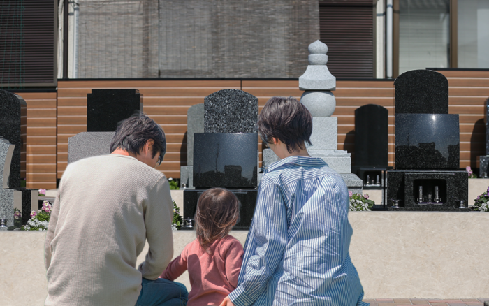 家族でお墓参りをする様子。複数世代が一緒にお参りしている後ろ姿