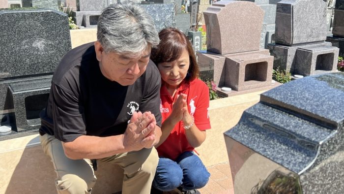お墓参りをする人の姿 手を合わせて祈る様子